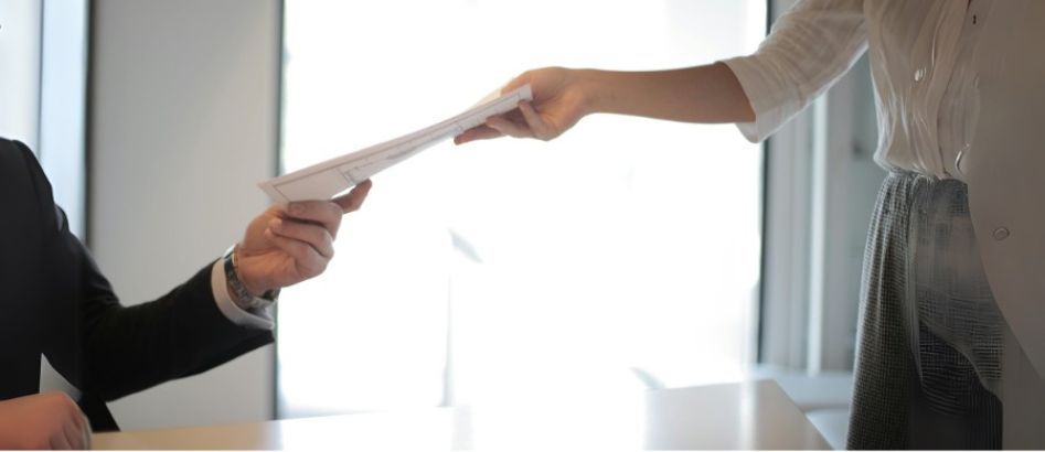 A shot of paper documents being exchanged in a job interview