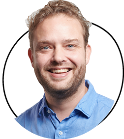 Smiling man in a blue shirt on a white background.