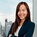 Smiling woman in a business suit with a city skyline background.