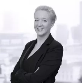 Woman in a business suit smiling with cityscape in the background.