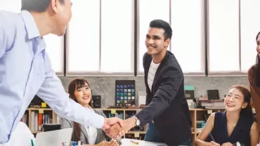 Team members exchanging handshakes in a meeting room, showing collaboration and teamwork.