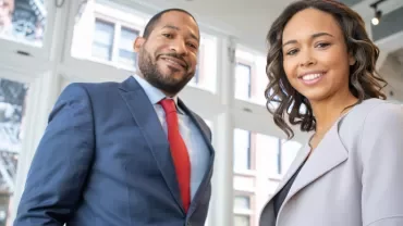 Two people smiling in a bright office environment.
