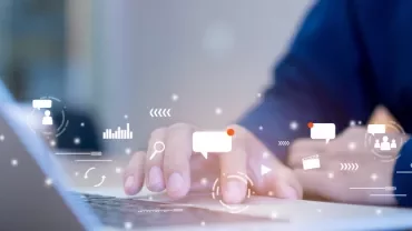 Person typing on a laptop with digital communication icons above the keyboard.