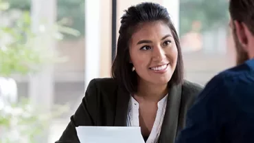 Woman smiling during a conversation with a man in an office.