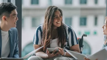 Indian female white collar worker in wheelchair discussion in office lounge with colleague