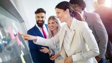 Group of business professionals brainstorming with sticky notes on a board.