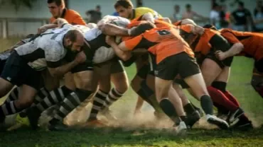 Rugby players in a scrum during a match on a grassy field.