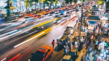 Busy city street at night with blurred lights and bustling markets.