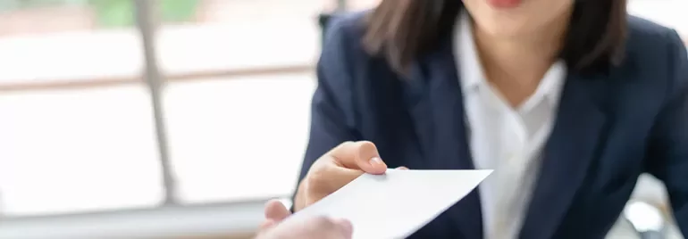 Woman handing over a business card in an office setting.