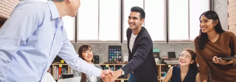 Team members exchanging handshakes in a meeting room, showing collaboration and teamwork.