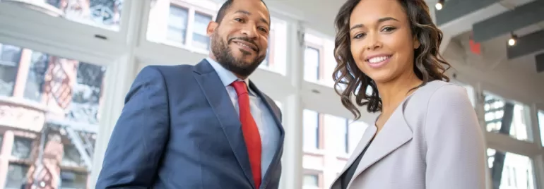Two people smiling in a bright office environment.