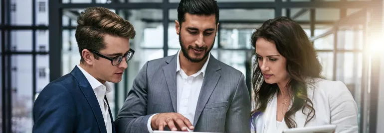 3 office workers looking at tablets in an office