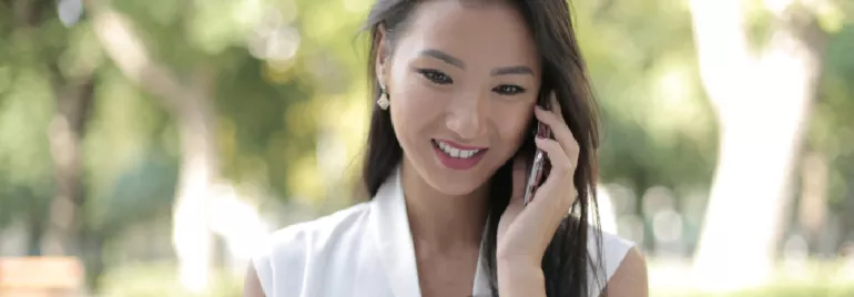 Woman smiling while talking on the phone outdoors.