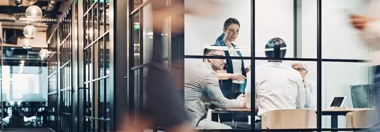 People in a modern glass-walled office having a meeting.