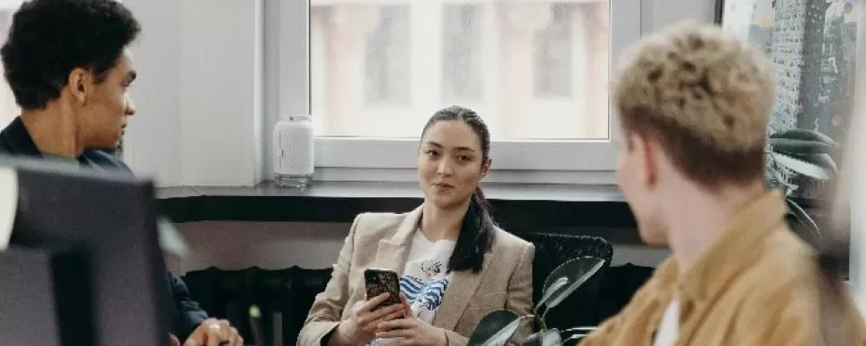 A group of three people having a meeting in an office setting.