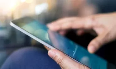 Close-up of hands using a tablet, soft focus background.