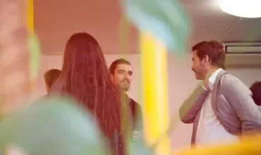 Group of people in casual conversation in an indoor setting with a warm ambiance.