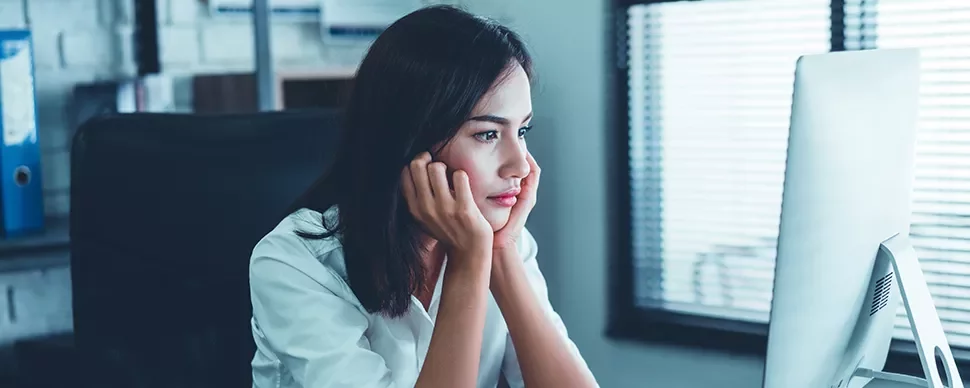 Woman in white shirt looking intently at a computer screen in an office.