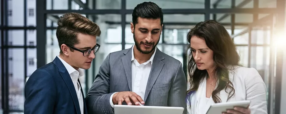 Three business professionals reviewing documents on tablets.
