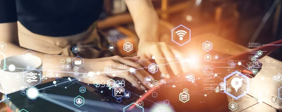 Person typing on a laptop surrounded by holographic network icons.