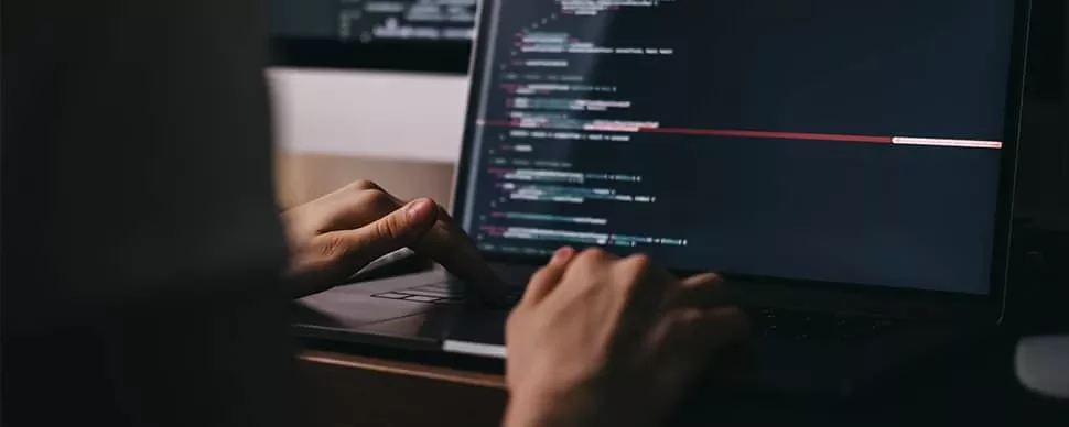 Person typing code on a dark-themed laptop screen.