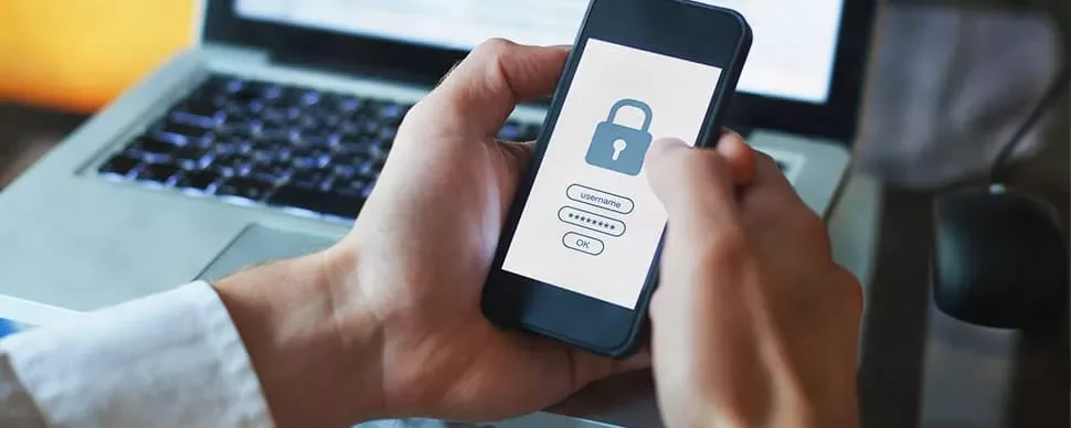 Person holding phone with security lock screen near laptop.