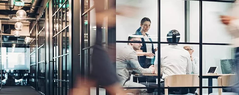 People in a modern glass-walled office having a meeting.