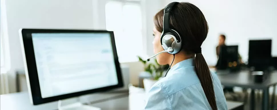 Person with headset works at a computer in an office setting.