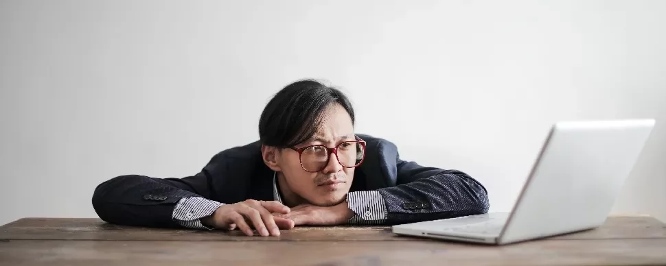 Man with glasses looking at a laptop on the table.