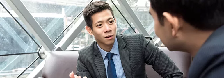 Two men in business attire having a conversation in a modern office setting.