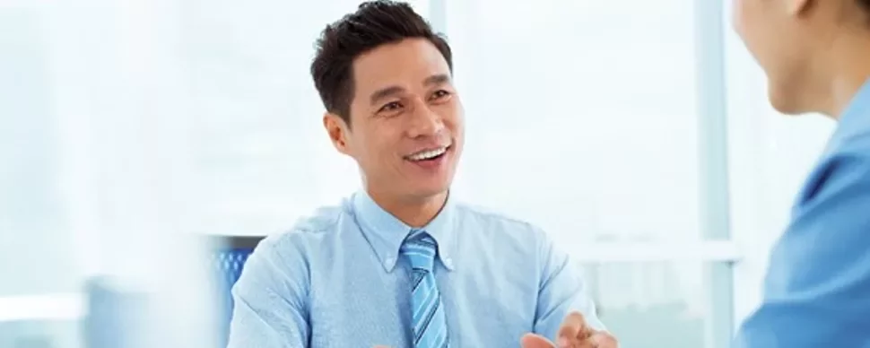 Two professionals having a conversation in a bright office setting.