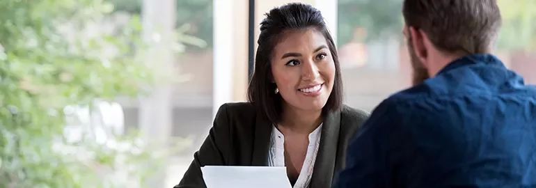 Woman smiling during a conversation with a man in an office.