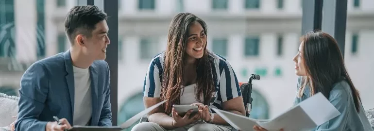 Three people having a discussion in an office space.