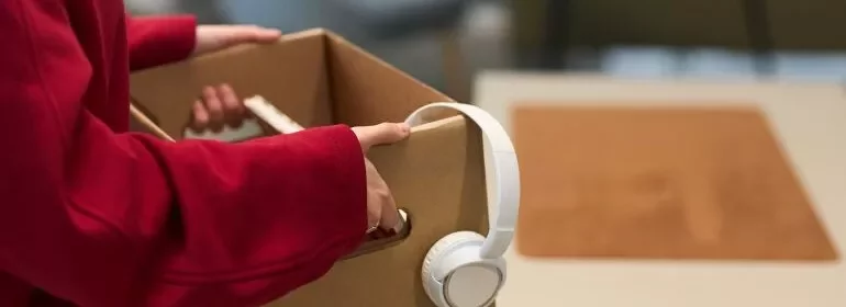 A person holding a box containing a pair of headphones.